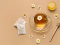 Une tasse de tisane pour le rhume et la toux, avec des sachets, du miel et des fleurs de camomille.