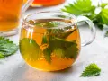 Une tasse de tisane d'ortie, aux feuilles vertes infusées dans un liquide ambré. Attention, la tisane ortie danger peut survenir si mal préparée.