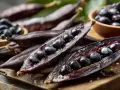Gousses de mucuna pruriens ouvertes, révélant des graines noires brillantes. Des graines sont aussi dans un bol en bois.