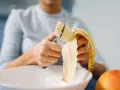 Une personne coupe une banane, riche en potassium, pour prendre soin de son cœur.