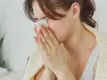 Femme se mouchant avec un mouchoir, cherchant des solutions pour comment arrêter le nez qui coule naturellement.