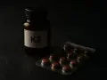 Flacon étiqueté K2 et blister de pilules sur fond sombre. Attention au vitamine k danger.