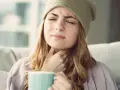 Femme souffrant d'extinction de voix, cherchant un remède miracle avec une tasse chaude.