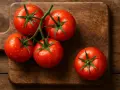 Cinq tomates rouges et juteuses, couvertes de gouttelettes d'eau, reposent sur une planche à découper en bois. Une faible calorie tomate pour une alimentation saine.