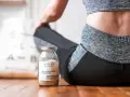 Un pot de collagène musculation à côté d'une femme en tenue de sport, prête pour sa séance.