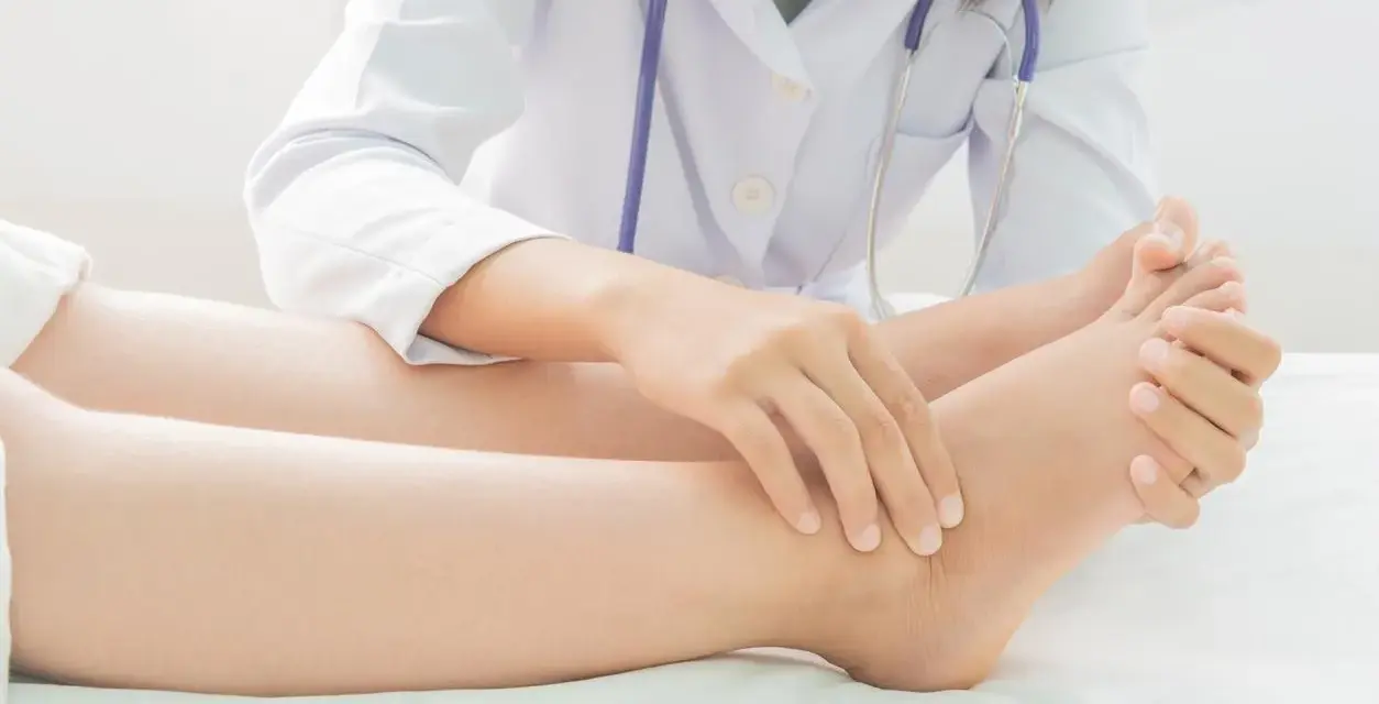 Un médecin examine le pied d'un patient, vérifiant la présence d'eau dans les jambes, un symptôme possible d'œdème.