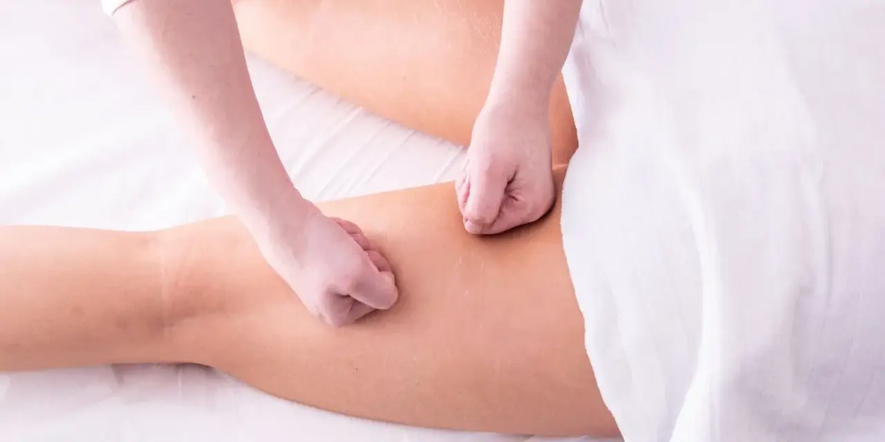 Mains effectuant un drainage lymphatique sur des jambes gonflées, pour soulager la rétention d'eau et améliorer la circulation.