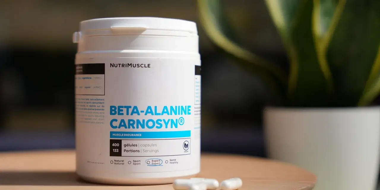 Bouteille de bêta-alanine Carnosyn® pour l'endurance musculaire, avec des capsules sur une table en bois.