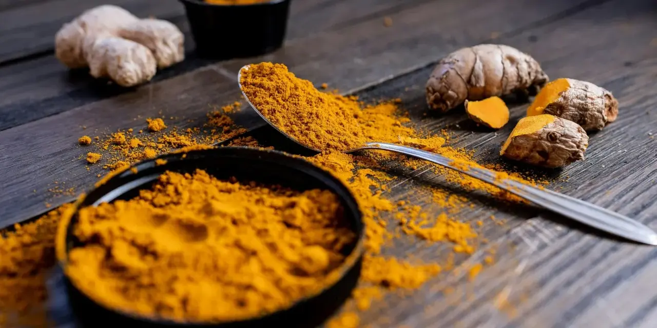 Poudre de curcuma et racines sur bois sombre. Le curcuma est connu pour ses nombreux cumin bienfaits.
