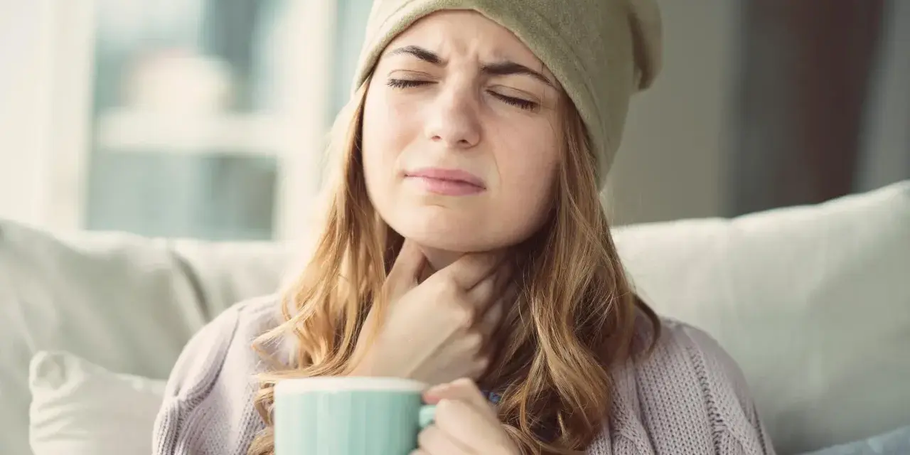 Femme souffrant d'extinction de voix, cherchant un remède miracle avec une tasse chaude.
