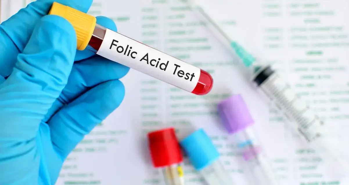Main tenue un tube à essai étiqueté "Folic Acid Test", prêt pour l'analyse des folates sériques.