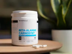Bouteille de bêta-alanine Carnosyn® pour l'endurance musculaire, avec des capsules sur une table en bois.