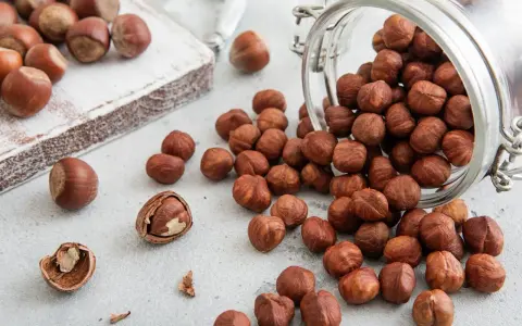 Des noisettes bienfaits : une poignée de ces fruits secs, certains dans un bocal renversé, d'autres sur une planche en bois, promettent une alimentation saine.