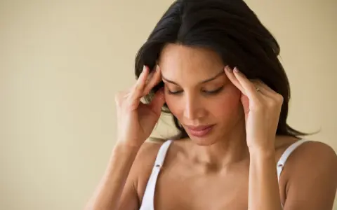 Femme se massant les tempes, cherchant à soulager une migraine en 30 secondes.