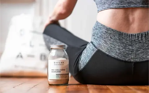 Un pot de collagène musculation à côté d'une femme en tenue de sport, prête pour sa séance.