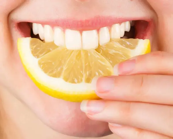 Une personne mord une tranche de citron. Est-ce que le citron est bon pour le foie ? La réponse est complexe, mais il est souvent cité pour ses bienfaits détoxifiants.