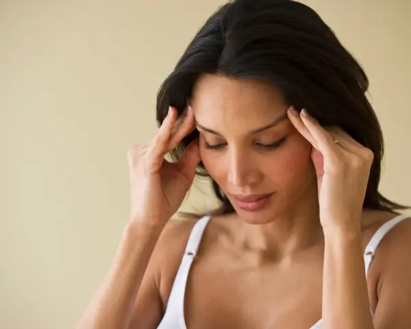 Femme se massant les tempes, cherchant à soulager une migraine en 30 secondes.