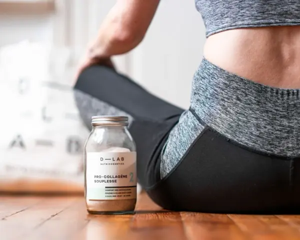 Un pot de collagène musculation à côté d'une femme en tenue de sport, prête pour sa séance.