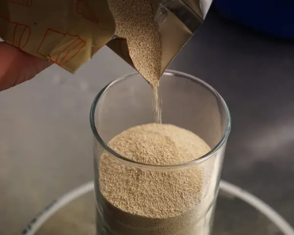 Une main verse de la levure de bière dans un verre. Découvrez les levure de bière bienfaits pour la santé.