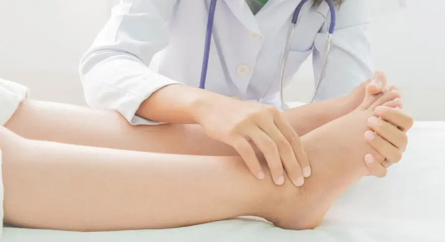Un médecin examine le pied d'un patient, vérifiant la présence d'eau dans les jambes, un symptôme possible d'œdème.