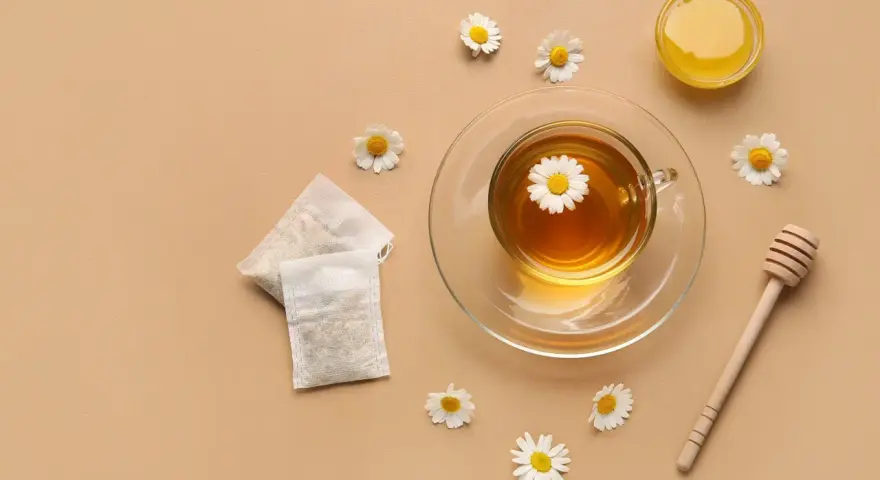 Une tasse de tisane pour le rhume et la toux, avec des sachets, du miel et des fleurs de camomille.