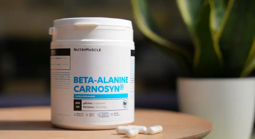Bouteille de bêta-alanine Carnosyn® pour l'endurance musculaire, avec des capsules sur une table en bois.