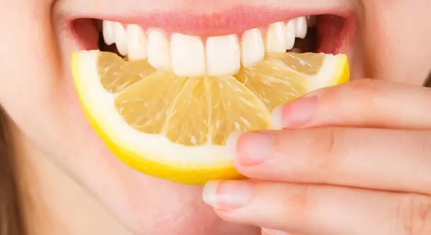 Une personne mord une tranche de citron. Est-ce que le citron est bon pour le foie ? La réponse est complexe, mais il est souvent cité pour ses bienfaits détoxifiants.