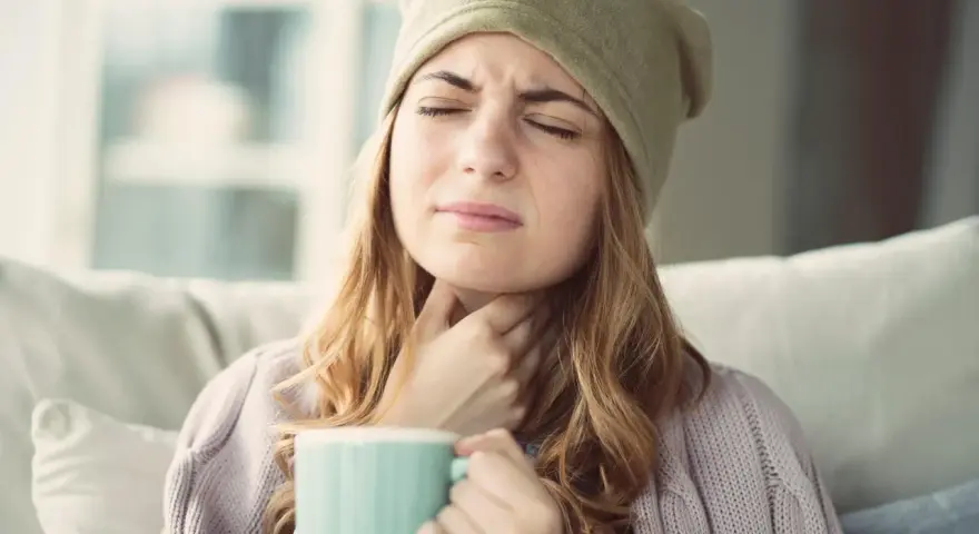 Femme souffrant d'extinction de voix, cherchant un remède miracle avec une tasse chaude.