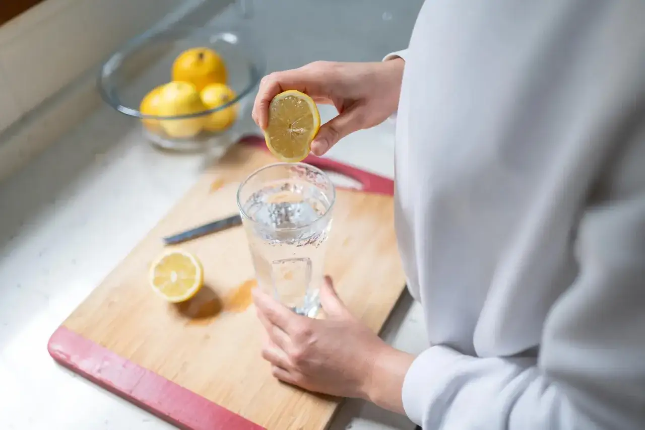 Une main presse un citron dans un verre d'eau. Est-ce que le citron est bon pour le foie ? Une question de bien-&ecirc;tre &agrave; explorer.