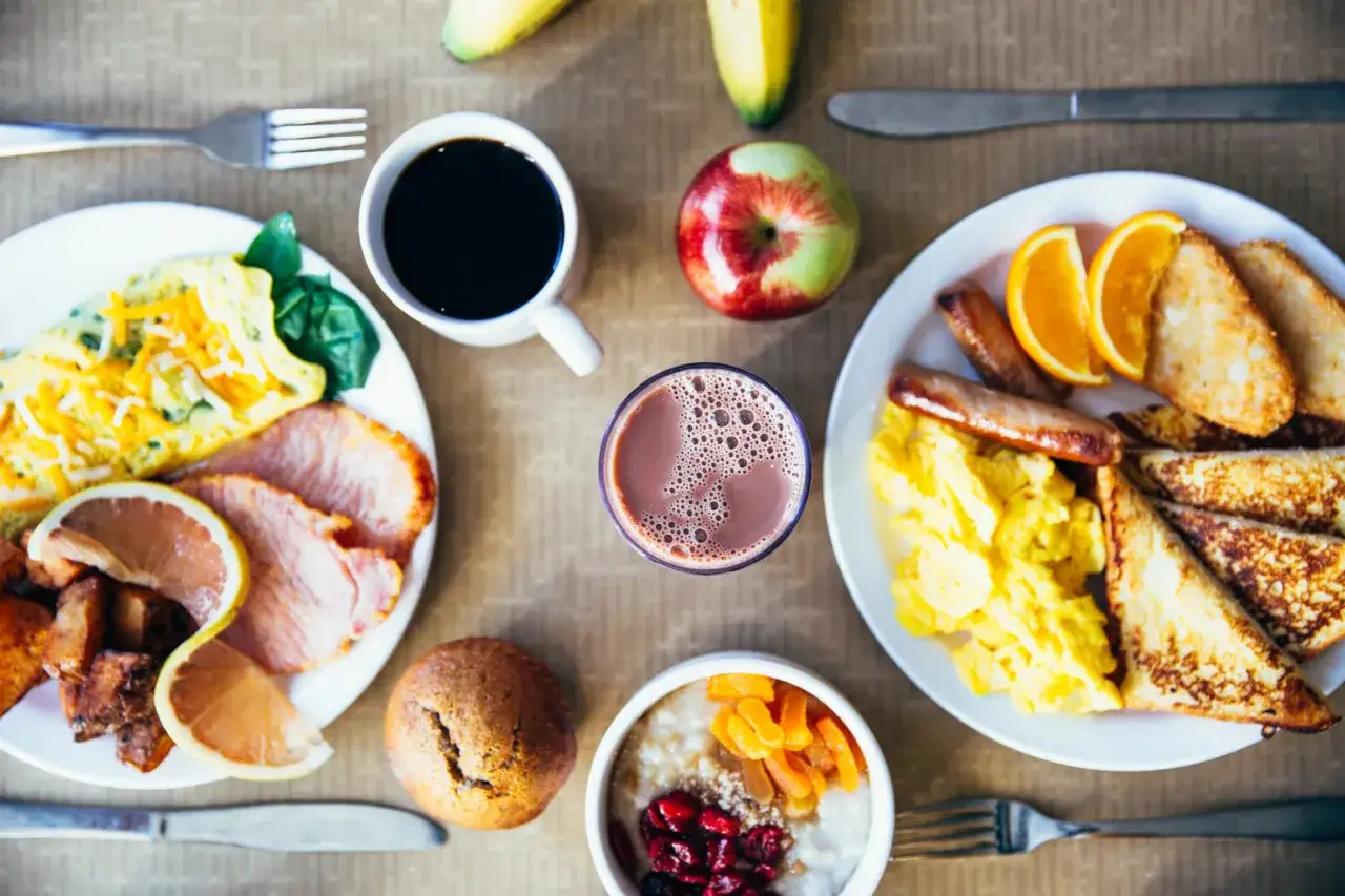 Un petit d&eacute;jeuner prise de masse copieux avec &oelig;ufs brouill&eacute;s, bacon, toasts, saucisses, fruits et caf&eacute;.