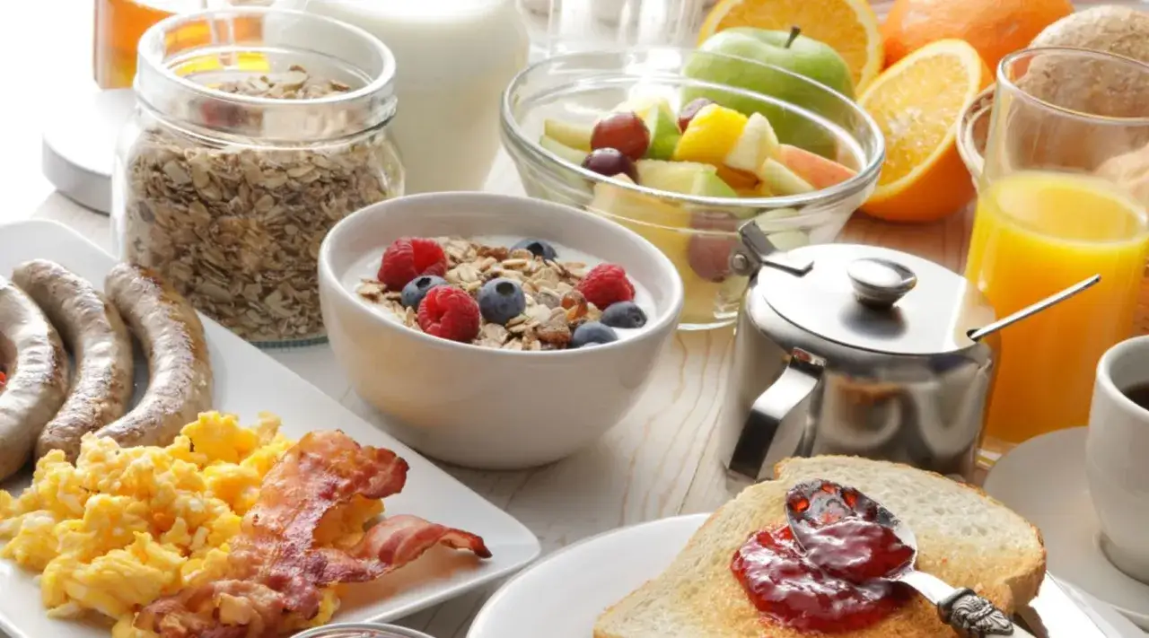 Un petit d&eacute;jeuner prise de masse copieux : &oelig;ufs brouill&eacute;s, bacon, saucisses, yaourt aux fruits, muesli, jus d'orange et toasts &agrave; la confiture.