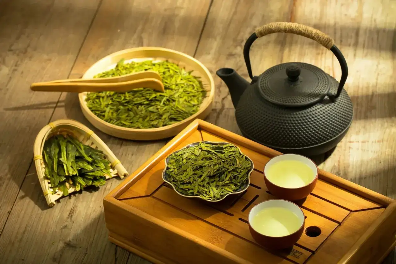 Thé vert bienfaits : une théière en fonte, des feuilles de thé séchées dans des paniers et des tasses de thé vert prêtes à être dégustées.