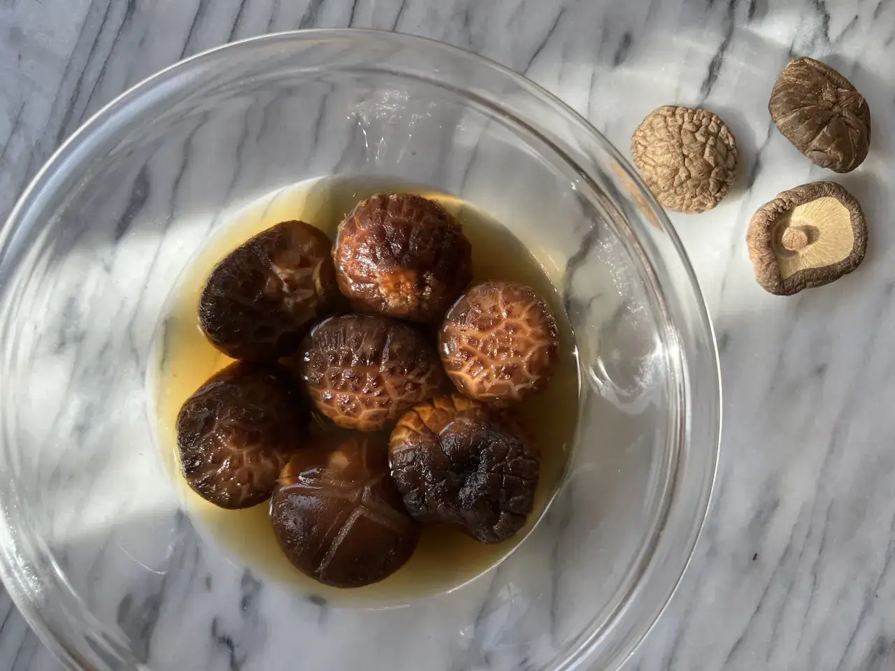 Champignons shiitake dans un bol, pr&ecirc;ts &agrave; r&eacute;v&eacute;ler leurs bienfaits. Quelques-uns sont s&eacute;ch&eacute;s sur le c&ocirc;t&eacute;.