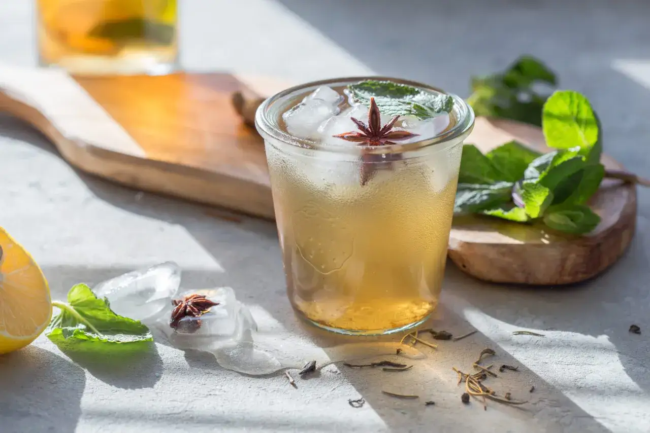 Un verre d'infusion &agrave; froid, garni de menthe et d'anis &eacute;toil&eacute;, avec des gla&ccedil;ons fondants et une tranche de citron.