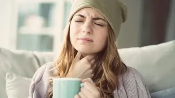 Femme souffrant d'extinction de voix, cherchant un remède miracle avec une tasse chaude.
