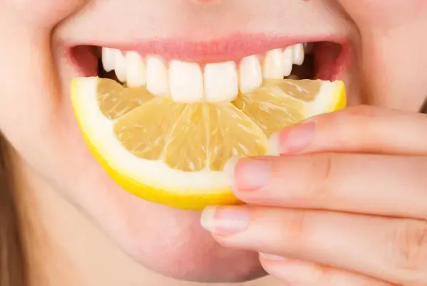 Une personne mord une tranche de citron. Est-ce que le citron est bon pour le foie ? La réponse est complexe, mais il est souvent cité pour ses bienfaits détoxifiants.