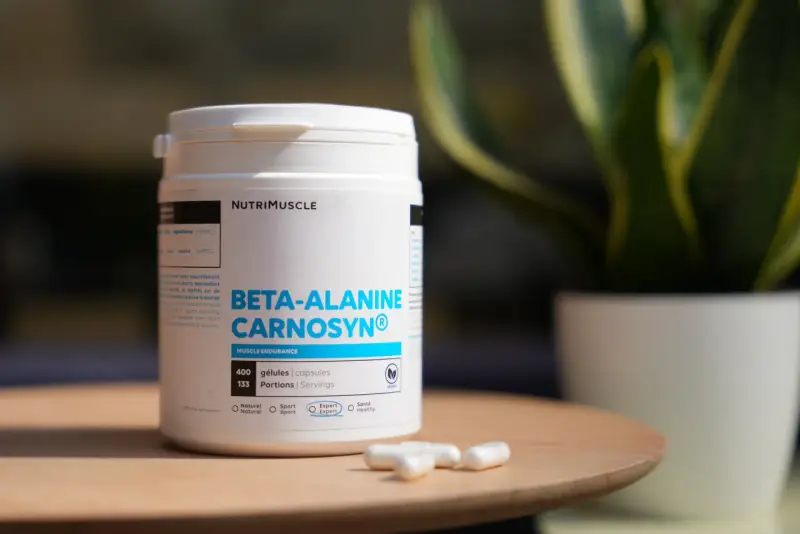 Bouteille de bêta-alanine Carnosyn® pour l'endurance musculaire, avec des capsules sur une table en bois.