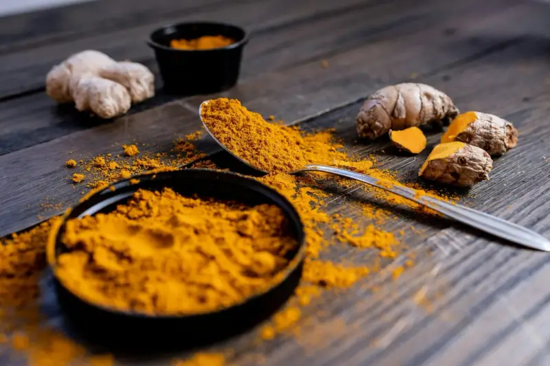 Poudre de curcuma et racines sur bois sombre. Le curcuma est connu pour ses nombreux cumin bienfaits.